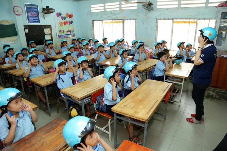 Các em học sinh trường tiểu học Nhị Xuân thực hiện hướng dẫn đội mũ bảo hiểm đúng quy cách