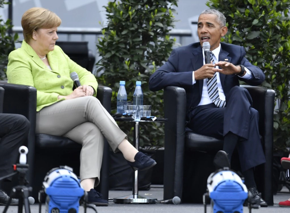 Cựu Tổng thống Mỹ ngồi cạnh Thủ tướng Đức Angela Merkel tại một sự kiện ở Berlin, Đức hồi tháng 5 (Ảnh: Alexander Koerner)