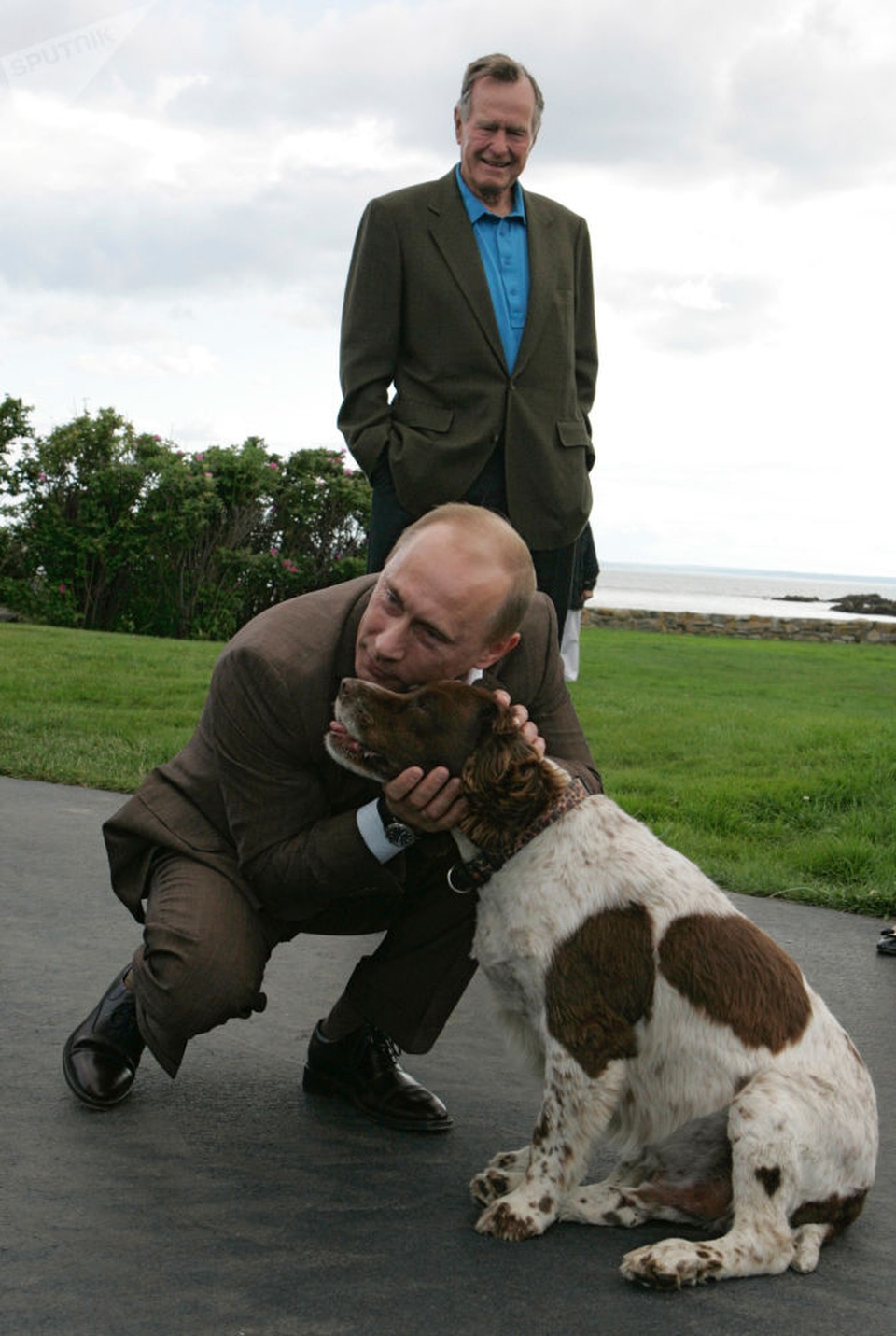 Tình yêu động vật của Tổng thống Putin - 8 Cựu Tổng thống Mỹ George W. Bush đứng cạnh nhìn nhà lãnh đạo Nga âu yếm một con chó.