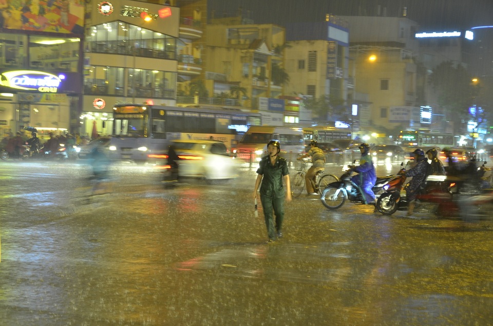 Một nữ thanh niên xung phong đứng giữa mưa để điều tiết giao thông