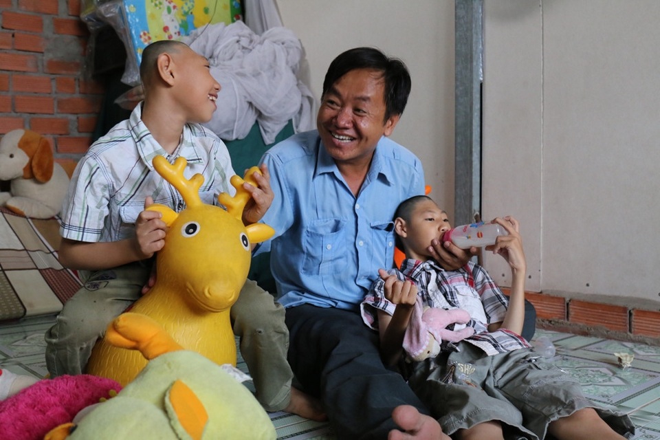 Giám khảo trào nước mắt trước giọng hát của người cha nuôi hai con teo não - 1 Anh Nghị bên hai người con mắc chứng teo não trong clip hậu trường.