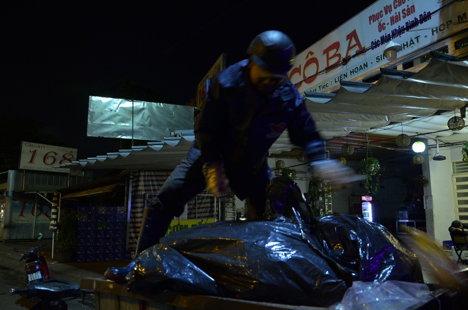 Người Sài Gòn đốt lửa sưởi ấm trong cái lạnh 20 độ C - 7 Do đặc thù công việc thu gom rác buổi sáng nên người đàn ông này phải mặc thêm áo mưa để giữ ấm cơ thể