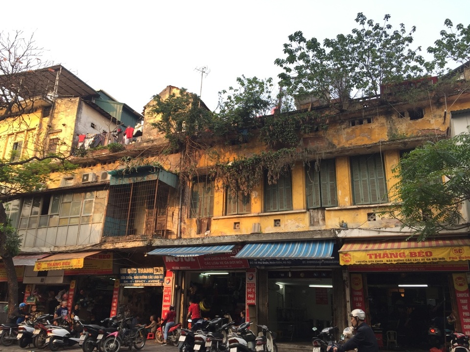 Thấp thỏm trong những ngôi nhà "chờ sập" giữa Thủ đô - 1 Nằm trên con phố Phủ Doãn đông đúc, có những căn nhà (đánh số từ 5A đến 7) được đưa vào sử dụng đã hơn 70 năm. Nhưng đến nay, khu nhà này đang rơi vào tình trạng xuống cấp nghiêm trọng. Nhìn từ bên ngoài, các mảng tường đã bong tróc gần hết, rễ cây dây leo bám sâu và lớp sơn cũng bị thời gian tàn phá khá nhiều. Nhiều người dân lo lắng khu nhà có thể đổ sập bất cứ lúc nào.
