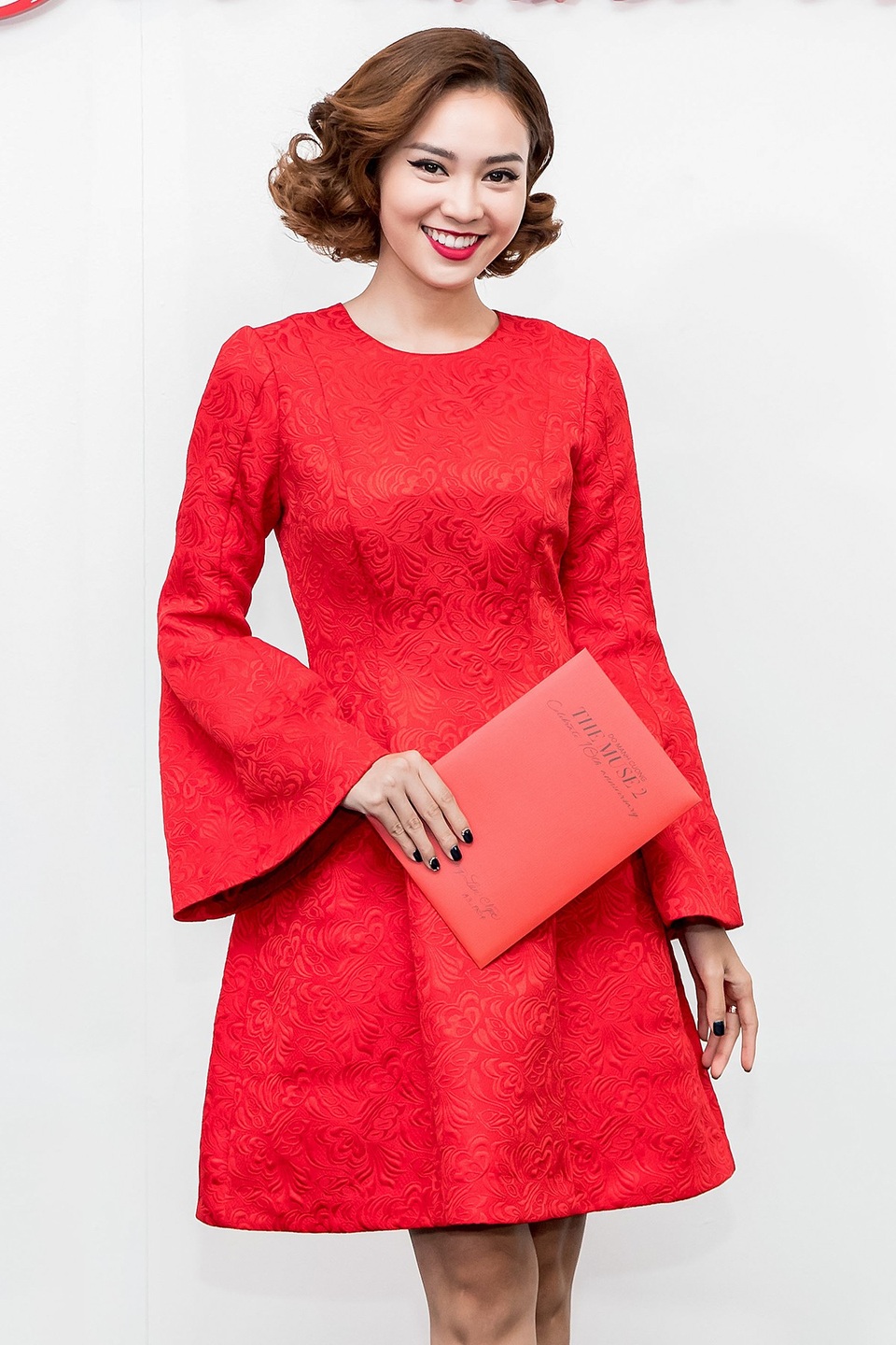 Diễn viên Ninh Dương Lan Ngọc duyên dáng, trẻ trung với chiếc đầm đỏ trên gối, được thực hiện trên nền vải gấm, có họa tiết với những đường nét mềm mại.