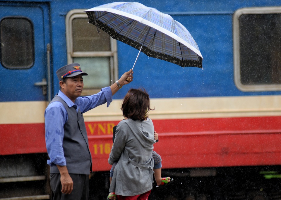 Ùn ùn "kéo nhau" đội mưa trở lại Sài Gòn - 7 Chú Nguyễn Đức Thích (52 tuổi, đã có 32 năm công tác ở ga Quảng Ngãi) dùng dù che cho khách lên tàu khỏi ướt. Chú cho biết, thấy trời mưa lớn nên cầm dù ra phụ giúp mọi người lên tàu không bị ướt để bắt đầu 1 năm mới thật suôn sẻ.