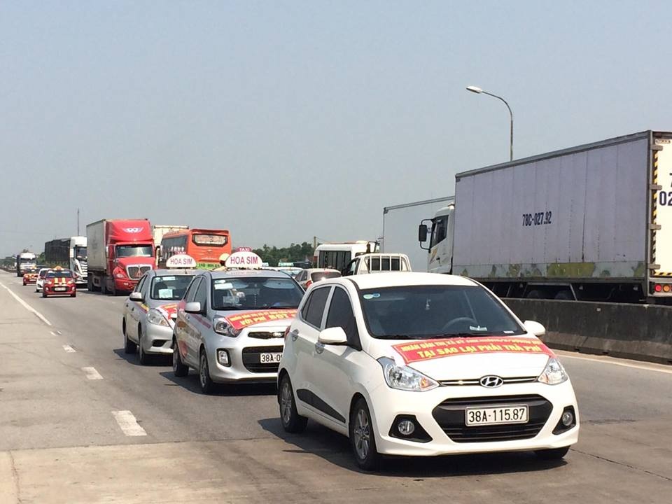 
Xe ô tô dán băng rôn đi qua trạm Cầu Rác để phản đối việc thu phí BOT
