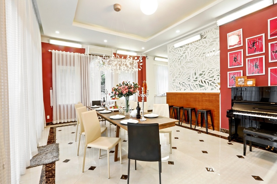 Kế đến là phòng bếp xa hoa như một căn bếp của gia đình hoàng gia. Một chiếc đàn piano được đặt cạnh bộ bàn ăn bằng gỗ, một chiếc đèn chùm sang trọng, một bình hoa, một cây nến.