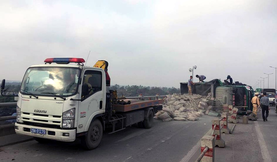 
Xe tải chở xi măng lật nghiêng trên cầu Thanh Trì. (Ảnh: Tiến Nguyên)
