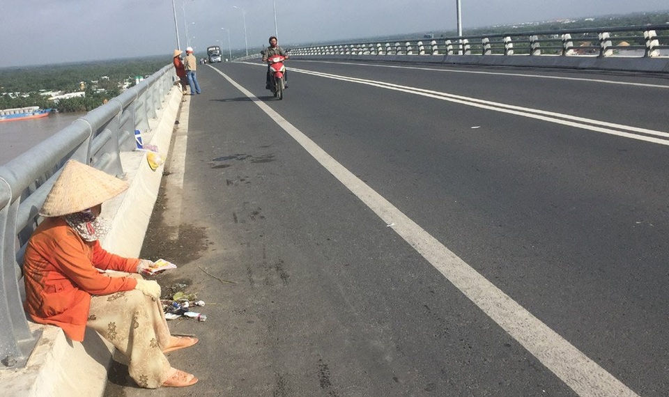 Bà cụ bán vé số và món tiền lớn từ người đàn ông lạ - 1 Bà Bông ngồi nép mình sát lan can thành cầu.