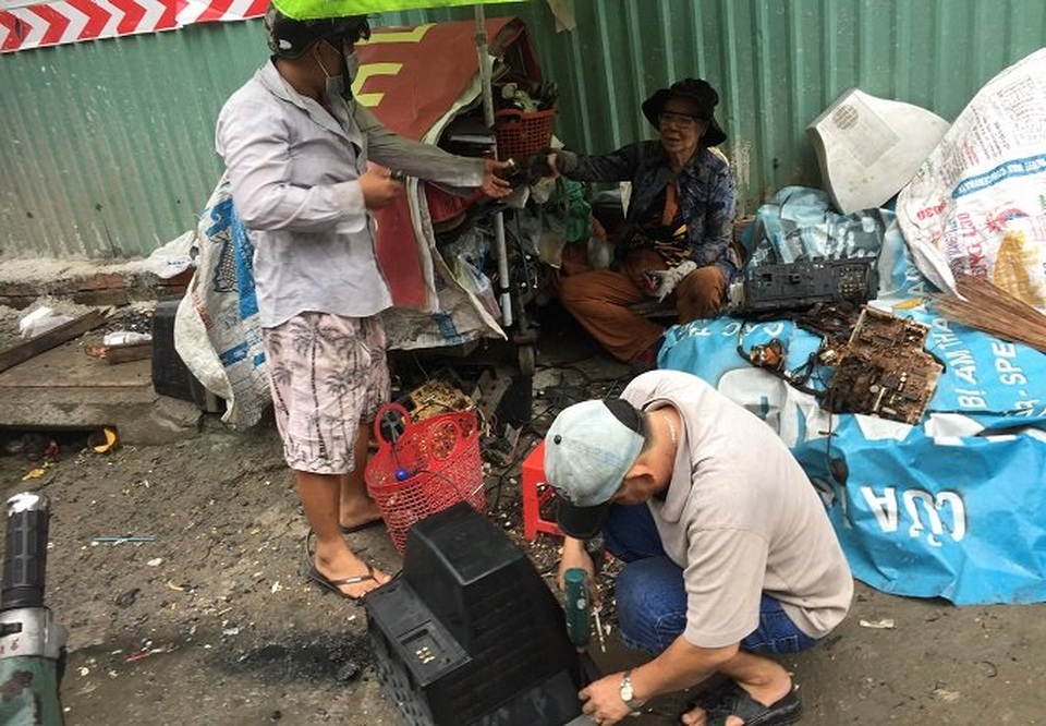 Người đàn bà buôn ti vi cũ: Tuổi xế chiều vất vả dưới cơn mưa - 1 Chiếc ti vi bỏ xuống đất. Anh Tâm đang mở ốc vít.