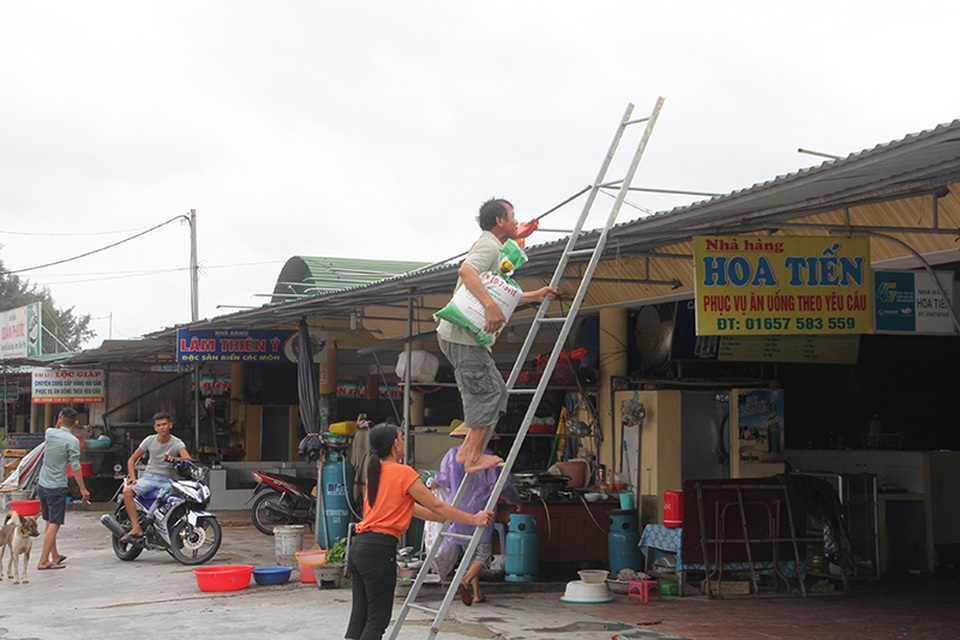 Miền Trung bắt đầu mưa, dân hối hả chạy "siêu bão" - 6 Nhiều hộ kinh doanh nhà hàng hải sản tại bãi biển này đang gắng sức kè mái tôn, cửa nhà hàng trước khi trở về nhà tránh bão.