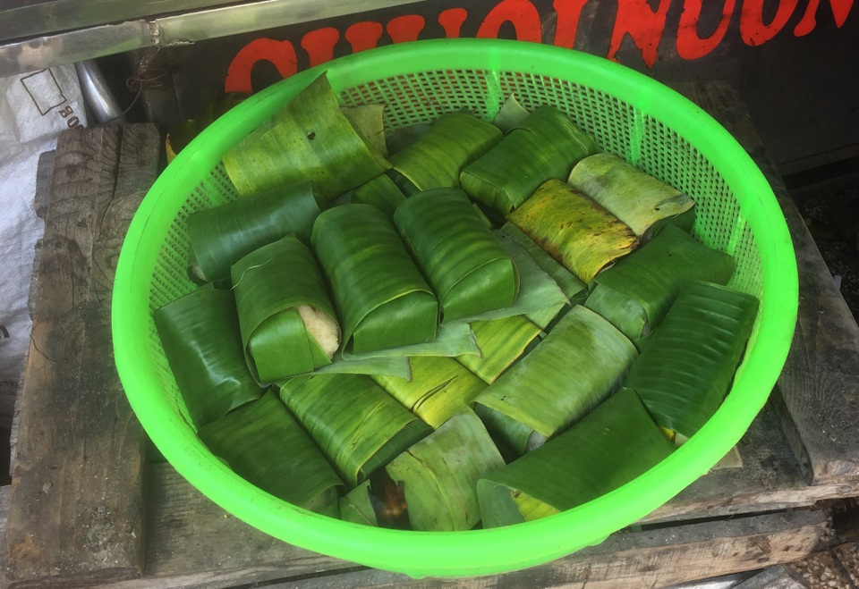 Quán chuối nướng trong hẻm Sài Gòn thu 15 triệu/ngày - 2 Chuối được bọc một lớp xôi nấu với dừa nạo, quấn trong lá và đem lên bếp nướng.
