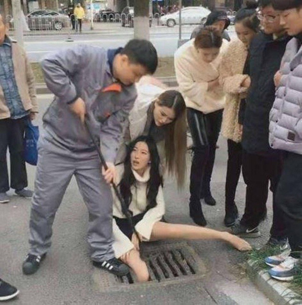 Gái xinh vừa đi vừa bấm điện thoại sụt chân xuống nắp cống kẹt cứng - 1 Không ai có thể ngờ được cô gái sẽ kẹt chân vào khe nắp cống nhỏ hẹp