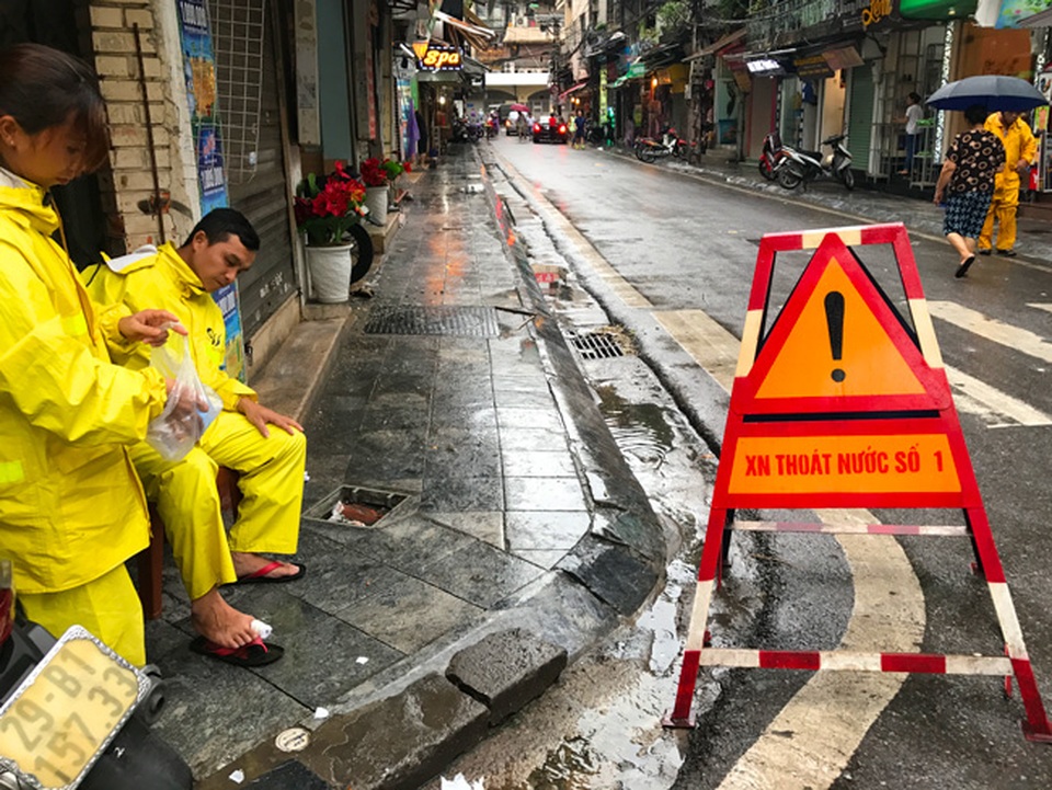 Khách Tây lạ lẫm xem phố cổ Hà Nội thành "biển nước" sau bão - 14 Một nhân viên thoát nước bị lật móng chân khi đang làm nhiệm vụ rút nước tại điểm này.