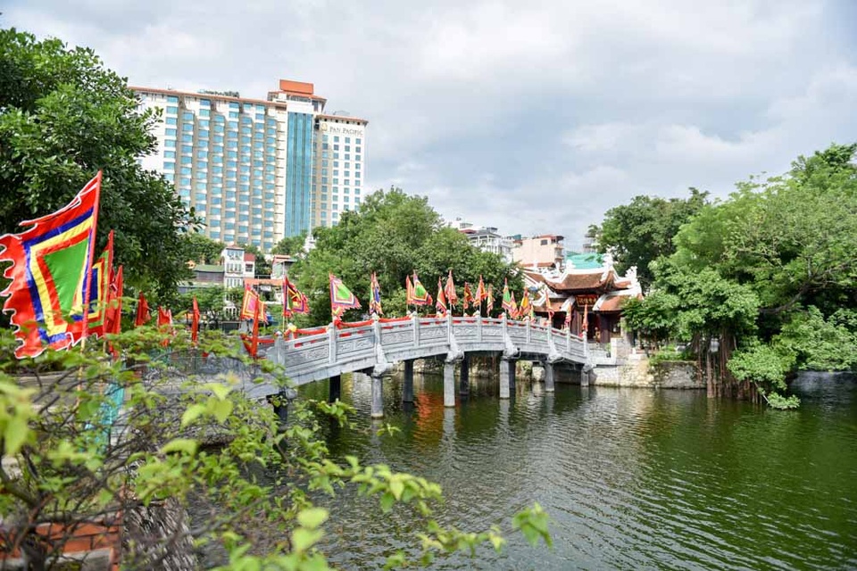 
Đền được nối với bờ bằng cây cầu đá bắc qua mặt hồ Trúc Bạch. Cầu dài 18m gồm năm nhịp, mỗi nhịp dài 3,6m, rộng 2,25m.

Theo một tích xưa truyền lại, nơi đây từng có một di tích do vua Lý Công Uẩn cho xây để thờ cặp chó mẹ - chó con thành thần. Chó con khi sinh ra, trên lông có những đốm ghép lại thành chữ Thiên tử ứng với việc vua Lý Công Uẩn lên ngôi (vua Lý tuổi Tuất).
