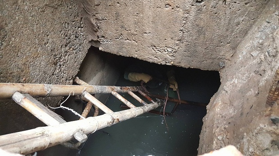 Người công nhân đầm mình trong làn nước cống đen ngòm, hôi hám, có chỗ nước ngập ngang cổ (Ảnh: Nhật Linh).