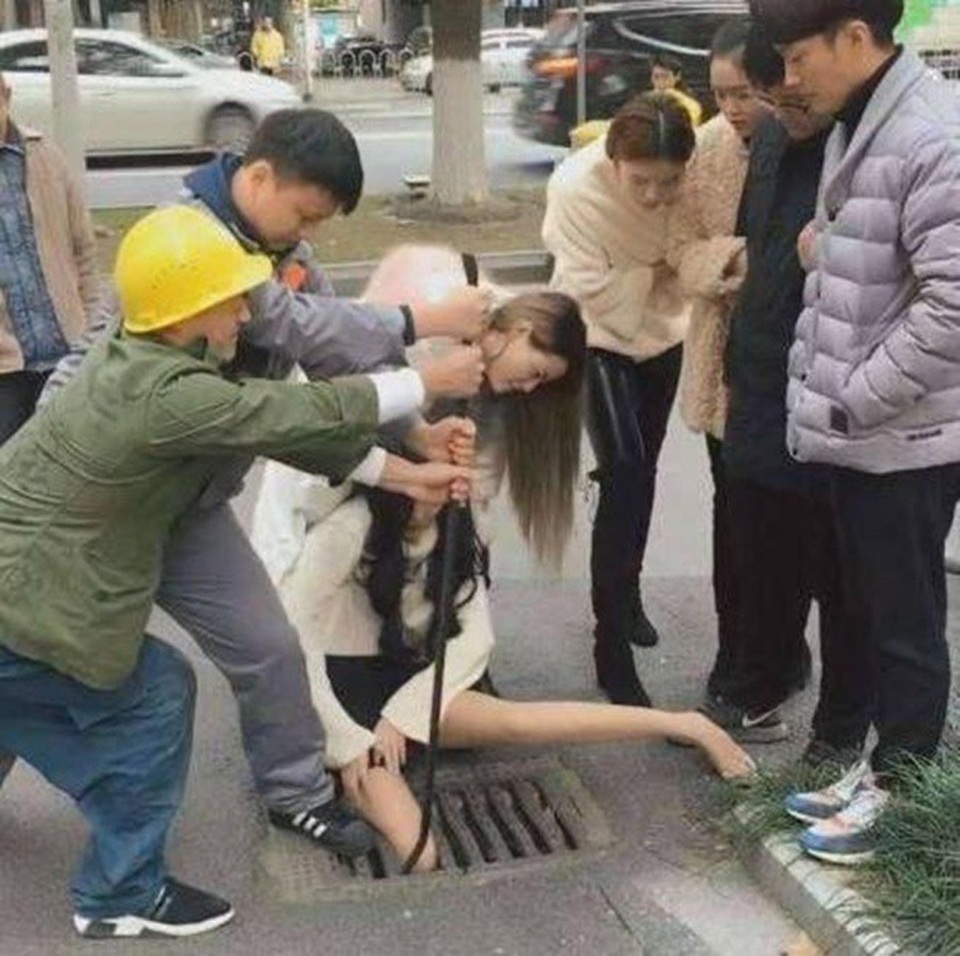 Gái xinh vừa đi vừa bấm điện thoại sụt chân xuống nắp cống kẹt cứng - 3 Kêu khóc trong khi được người đi đường cứu giúp