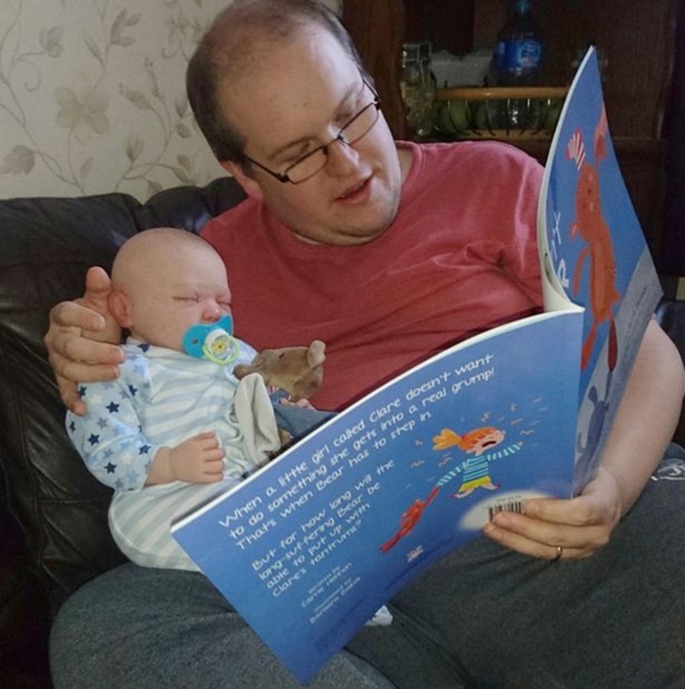 Không thể sinh con, cặp vợ chồng rủ nhau nuôi búp bê - 4 Terry đọc sách cho búp bê