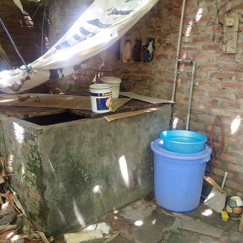 "Sống liều" ở điểm nóng sốt xuất huyết - 5 Thùng chứa nước sinh hoạt đặt cạnh nhà vệ sinh, lá tre rụng xuống phủ đầy mặt nước.