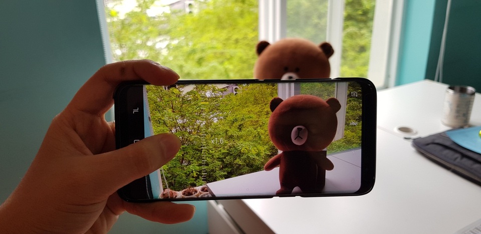 Những thủ thuật hay từ màn hình vô cực và camera của Galaxy S8 - 6 Khi máy ảnh đang ở chế độ chờ chuẩn bị chụp, bạn chỉ cần dùng một tay giữ nhẹ phím chụp và kéo lên xuống ở thanh Zoom ảnh. Điều thú vị nhất là bạn có thể dễ dàng nhìn thấy mức độ zoom mình mong muốn ngay trên thanh điều khiển này.