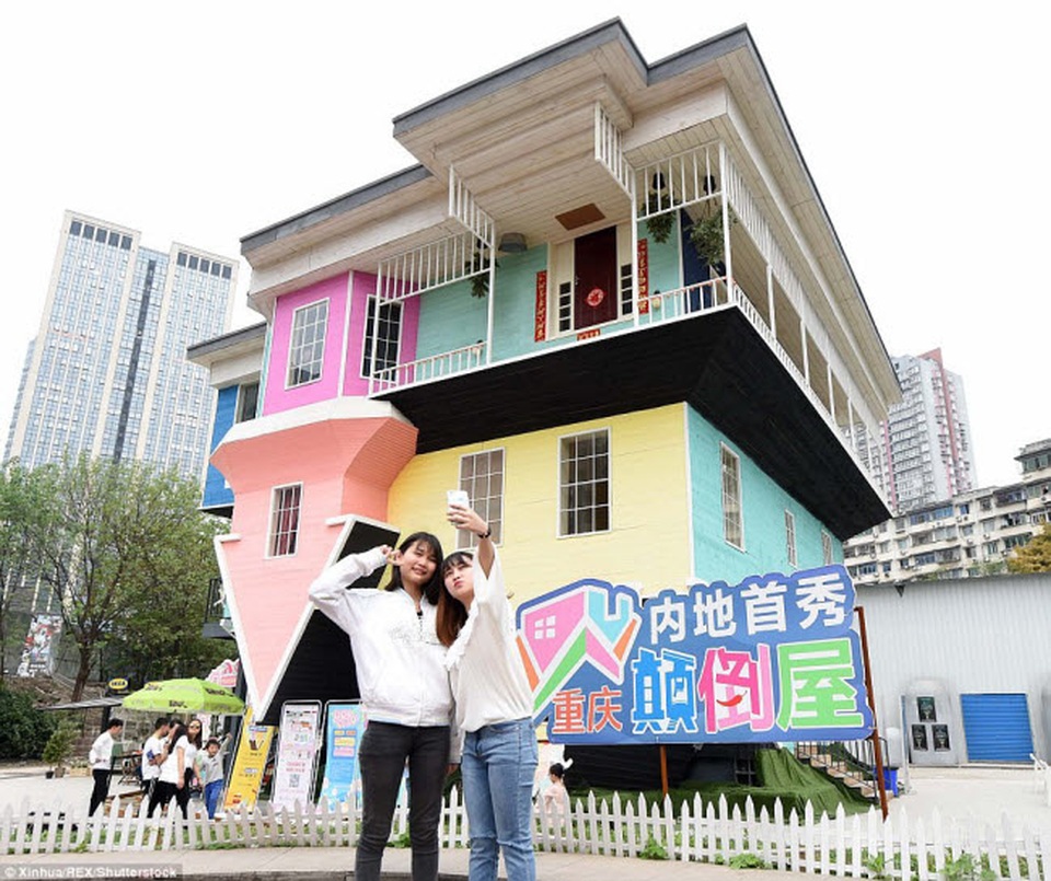 Thử cảm giác lạ trong những ngôi nhà lộn ngược "độc" nhất thế giới - 7 Du khách chụp ảnh trước một ngôi nhà lộn ngược nhiều màu sắc ở thành phố Trùng Khánh, Trung Quốc.