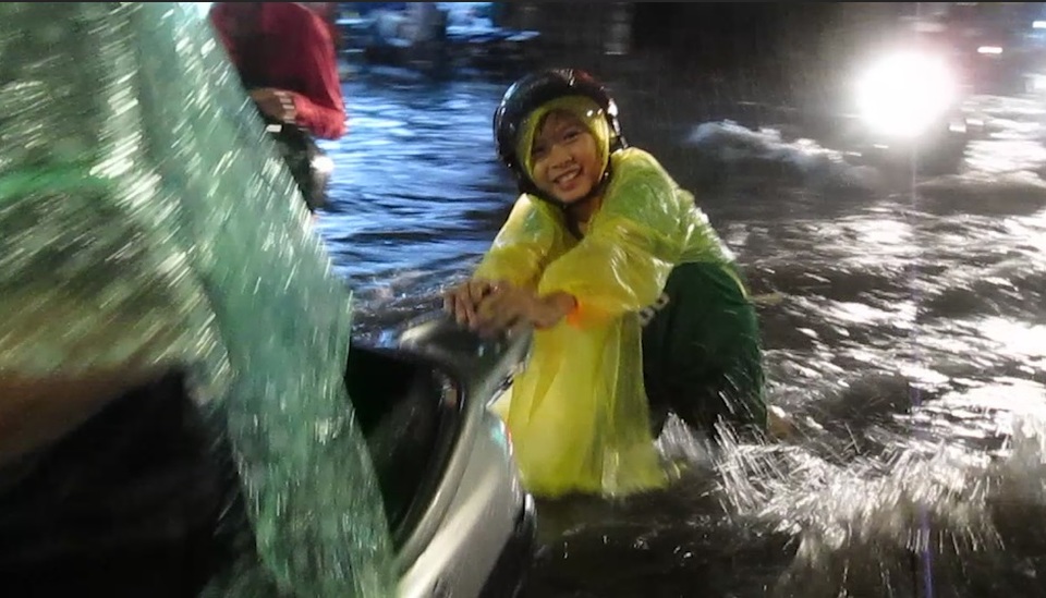 Em bé vui vẻ đẩy xe giúp mẹ qua điểm ngập nước