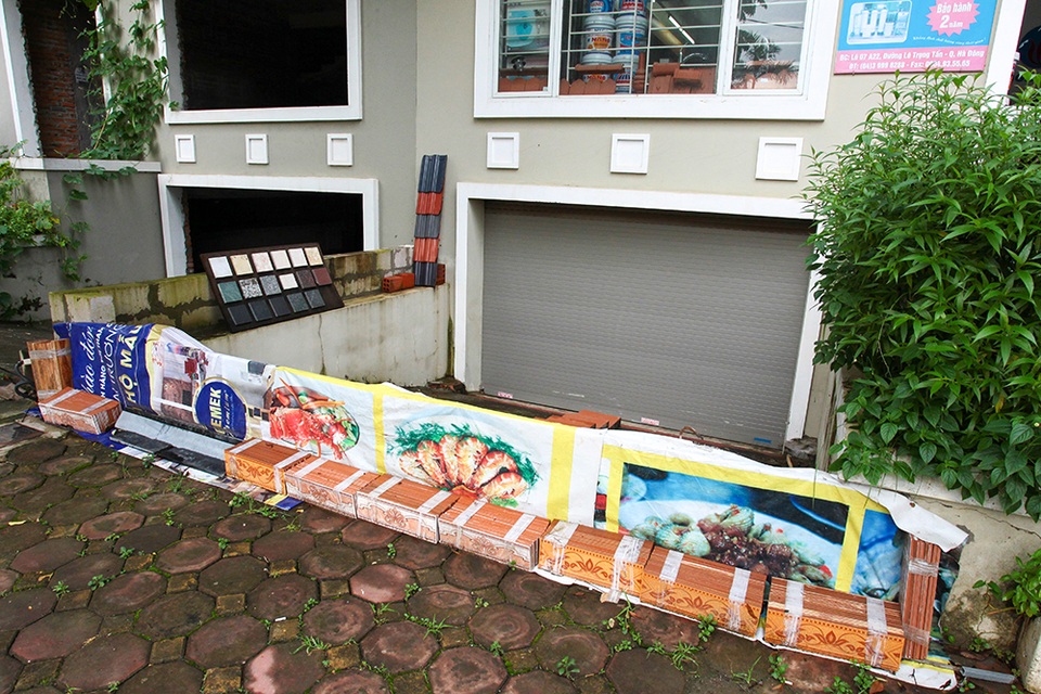 Hà Nội: Người dân hối hả “đắp đê” trước cửa nhà phòng mưa ngập sau bão - 8
Không chỉ dùng bao cát, người dân ở dây còn dựng những tấm phản, gạch lên thành bờ cao khoảng nửa mét để chống ngập.