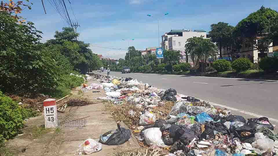 Vụ “mắc màn” chặn xe rác: Không để một nhóm người ảnh hưởng cả thành phố - 1 Rác ngập dưới lòng đường trên QL32 thuộc phường Phú Thịnh (Ảnh: VNN)