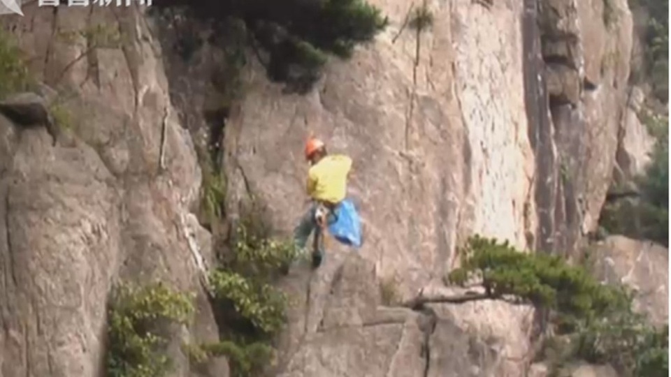 Nhân viên dọn rác thải cheo leo trên vách núi thẳng đứng