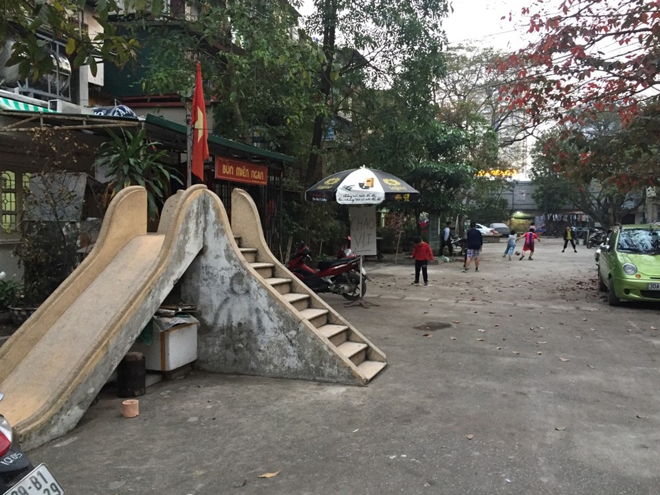 Hàng loạt sân chơi cho trẻ em “đắp chiếu” giữa Hà Nội - 14 Sân chơi của khu tập thể Giảng Võ chỉ có duy nhất chiếc cầu trượt không ai đoái hoài. Ở phía ngoài, khoảng sân cũng đã bị người dân lấy gần hết để bày hàng quán ăn.