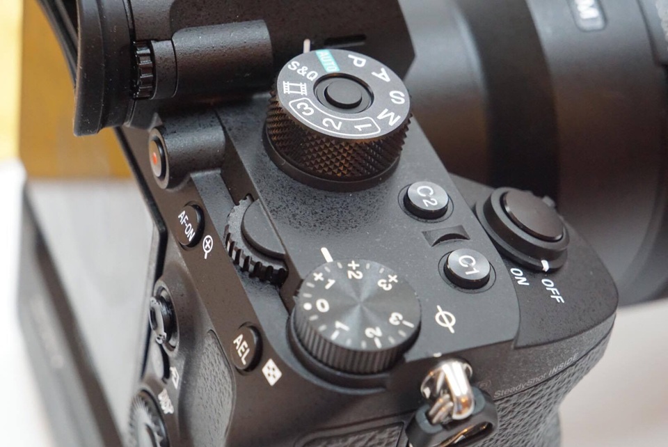 Phía trên là hệ thống điều khiển sắp xếp thông minh và độ nảy tốt giúp cho người dùng có thể lựa chọn nhanh các chế độ để chụp ảnh, bao gồm: vòng tròn xoay để lựa chọn các chế độ chụp, vòng tròn xoay bù sáng, phím joystick 8 chiều, vòng chỉnh lấy nét ống kính, phím custom 3, phím menu hay phím AEL....