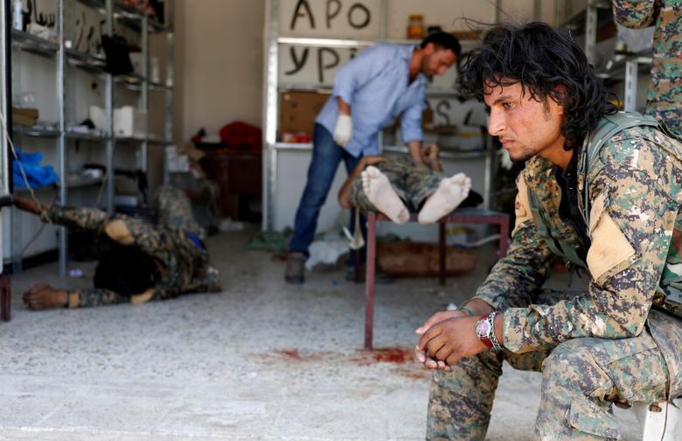 Bên trong bệnh viện dã chiến ở “chảo lửa” Syria - 1 Cuộc chiến giữa Các Lực lượng Dân chủ Syria (SDF) và các tay súng thuộc tổ chức Nhà nước Hồi giáo tự xưng (IS) đang diễn ra căng thẳng tại thành phố Raqqa của Syria. Với sự hỗ trợ của liên quân do Mỹ dẫn đầu, SDF đã giải phóng một số khu vực rộng lớn tại Raqqa khỏi sự chiếm đóng của IS. Trong ảnh: Một binh sĩ SDF ngồi trước cửa một bệnh viện dã chiến tại Raqqa trong khi các đồng đội đang được điều trị bên trong.