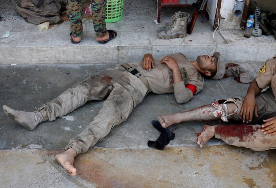 Bên trong bệnh viện dã chiến ở “chảo lửa” Syria - 6 Tại những khu vực chưa được giải phóng ở Raqqa, IS vẫn đang cố thủ và tấn công mạnh quân đội chính phủ cũng như các lực lượng do Mỹ hậu thuẫn với hy vọng có thể giữ lại thành trì này. Trong ảnh: Lực lượng SDF bị thương nằm bên ngoài một bệnh viện dã chiến tại Raqqa.