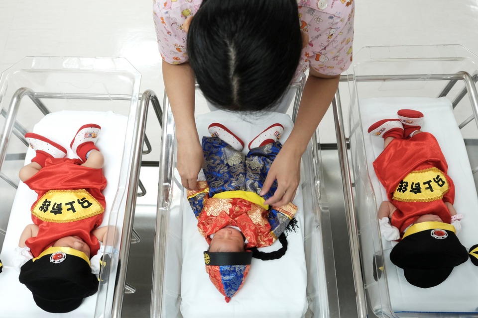 Thế giới tưng bừng đón năm mới Đinh Dậu - 18 Một nữ y tá mặc quần áo truyền thống của người Trung Quốc cho các bé sơ sinh nhân dịp năm mới tại phòng hậu sinh ở bệnh viện Paolo Chockchai, Bangkok, Thái Lan. (Ảnh: Reuters)