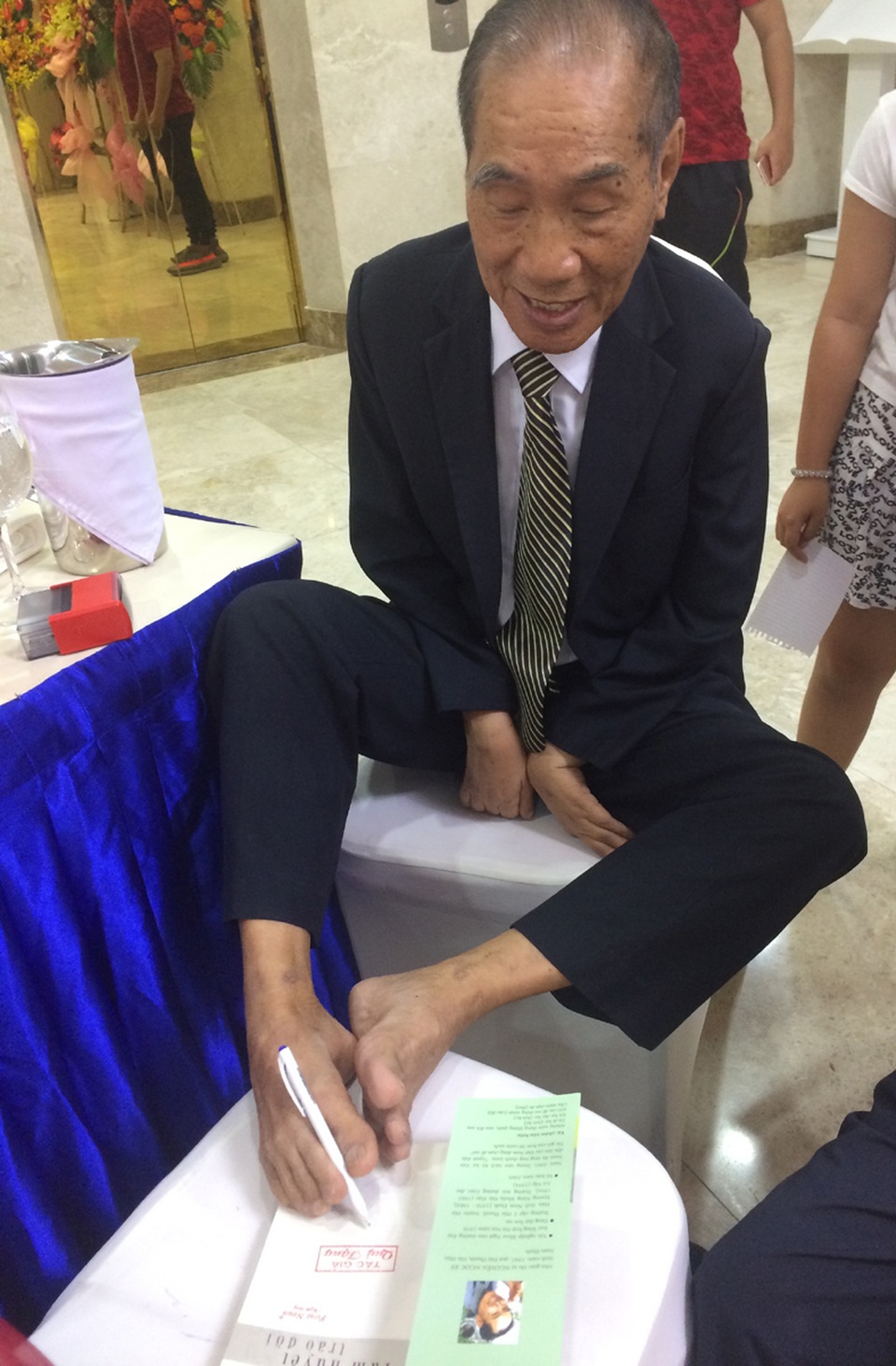 “Tâm huyết trao đời” của Nhà giáo ưu tú Nguyễn Ngọc Ký - 2 Thầy Nguyễn Ngọc Ký dùng đôi chân của mình ký tặng sách cho bạn đọc.
