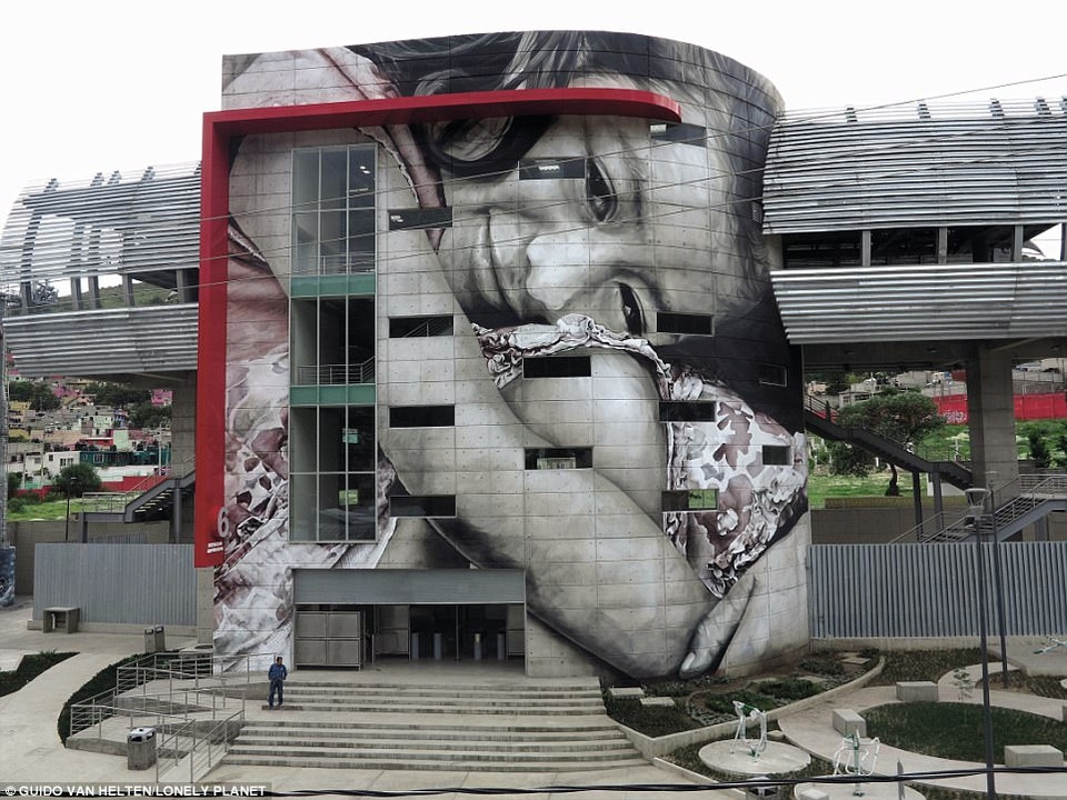 Một cô gái đang cúi xuống ôm đầu gối trong bức hình vẽ trên tường ở một tòa nhà. Đây là tác phẩm của nghệ sỹ Guido van Helten trên phố San Andres de la Canada ở Mexico City.