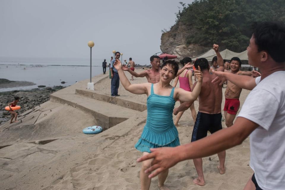 Người Triều Tiên vui chơi “thả ga” trên bãi biển - 1 Hầu hết người lao động Triều Tiên đều tận dùng từ 4-5 ngày nghỉ phép trong năm để đi du lịch cùng nhau. Bãi biển ở thành phố biển Nampo phía tây nam thủ đô Bình Nhưỡng là một trong những điểm đến yêu thích của người dân Triều Tiên. Trong ảnh: Những người đàn ông và phụ nữ Triều Tiên nhảy múa cùng nhau trên bãi biển. (Ảnh: AFP)