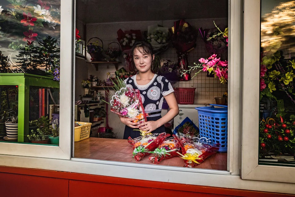 Khoảnh khắc bình dị trong cuộc sống thường ngày tại Triều Tiên - 3 Một cửa hàng bán hoa gần Đài tưởng niệm Mansudae ở thủ đô Bình Nhưỡng. Những người tới thăm đài tưởng niệm này thường mua hoa và đặt trước tượng đài của hai nhà lãnh tụ Triều Tiên Kim Nhật Thành và Kim Jong-il.