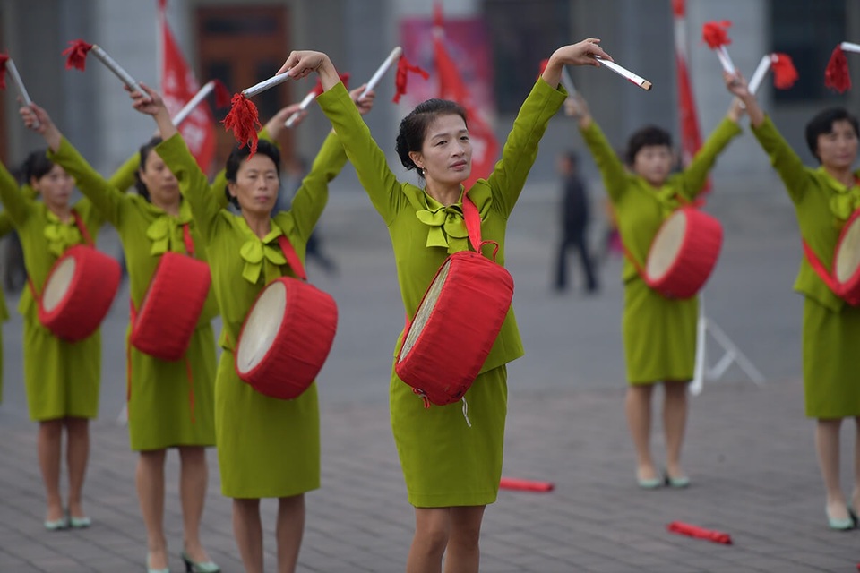 Các bà nội trợ Triều Tiên mặc đồng phục vẫy cờ tại Bình Nhưỡng để khích lệ tinh thần công nhân làm việc tại các nhà máy vào buổi sáng. (Ảnh: Straitstimes/Desmond Foo)