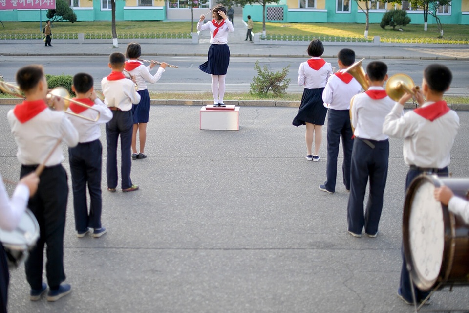 Học sinh Triều Tiên đeo khăn quàng đỏ chào đón bố mẹ trên đường từ cơ quan về vào buổi chiều tối. (Ảnh: Straitstimes/Desmond Foo)