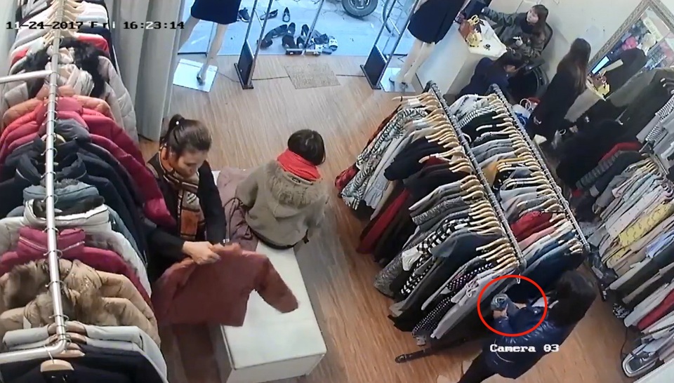 Người phụ nữ cuộn tròn chiếc quần bò rồi giấu trong người. (Ảnh cắt từ clip)