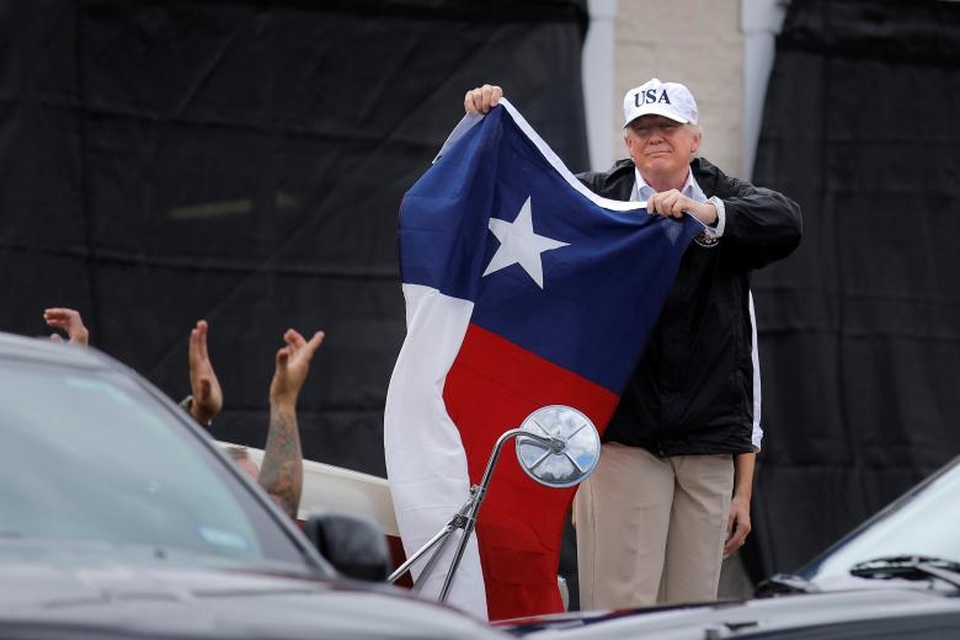 Tổng thống Trump vào tâm bão lũ tại Texas - 2 Đây là chuyến thị sát đầu tiên của Tổng thống Trump tới Texas từ sau khi cơn bão Harvey, cơn bão được đánh giá là mạnh nhất trong vòng 50 năm qua, đổ bộ vào khu vực này. Ông Trump đã gặp gỡ các lãnh đạo địa phương và người dân để nghe báo cáo về tình hình thiên tai. Trong ảnh: Tổng thống Trump cầm cờ của bang Texas gặp gỡ người dân ở Corpus Christi. (Ảnh: Reuters)