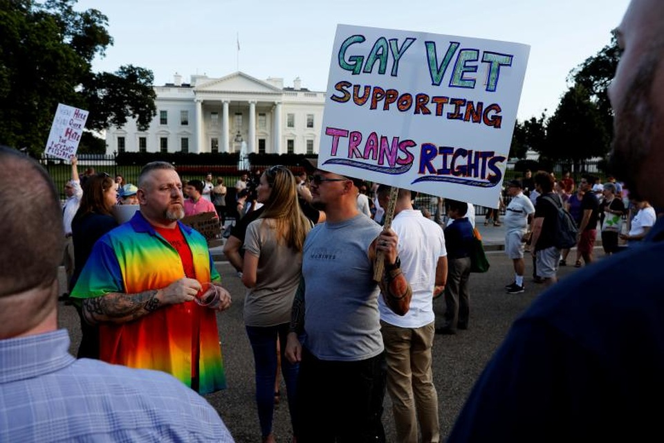 Biểu tình rầm rộ vì lệnh cấm người chuyển giới nhập ngũ của Tổng thống Trump - 3 Nhiều người cho rằng Tổng thống Trump đã vi phạm nhân quyền khi đưa ra quy định này vì “quyền của người chuyển giới cũng là quyền của con người”. Trong ảnh: Người biểu tình mang theo biểu ngữ và mặc áo in cờ của cộng đồng LGBT biểu tình bên ngoài Nhà Trắng.