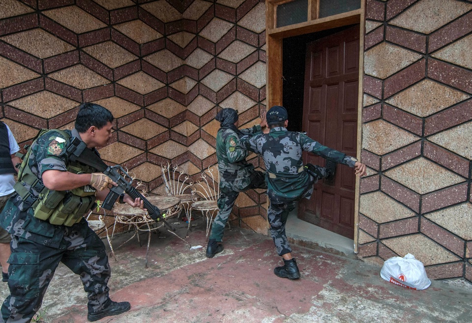 Chiến sự ác liệt tại thành phố bị phiến quân bao vây ở Philippines - 4 Ông Eduardo Ano cho biết các phiến quân đã tích trữ lương thực cũng như vũ khí trong các nhà thờ, trường học, các vị trí dân sự cũng như mạng lưới đường hầm dưới lòng đất để chuẩn bị cho một cuộc chiến “dài hơi” với quân đội chính phủ. Trong ảnh: Các binh lính và cảnh sát Philippines đạp cửa xông vào một ngôi nhà để truy lùng các phiến quân ẩn náu. (Ảnh: Reuters)