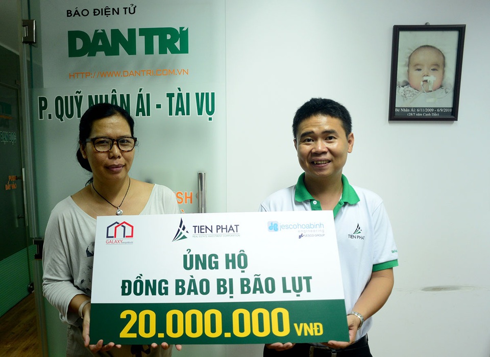 Nhà báo Lý Thị Toàn Thắng, Trưởng Văn phòng phía Nam báo điện tử Dân trí (trái) nhận số tiền ủng hộ đồng bào bị lũ lụt của Công ty TNHH đầu tư địa ốc Tiến Phát do ông Nguyễn Trí Cường, Phó phòng Marketing đại diện trao