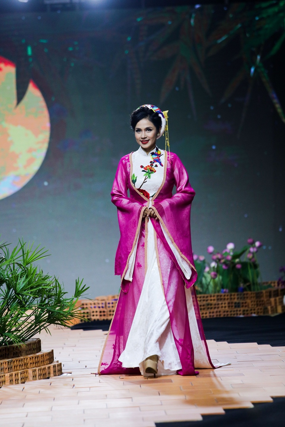 Cô khoác áo tứ thân ngoài áo dài, đầu đội mấn, cài trâm, bước đi uyển chuyển, thư thái. Người đẹp vẫn giữ được vóc dáng mảnh mai, thon thả.