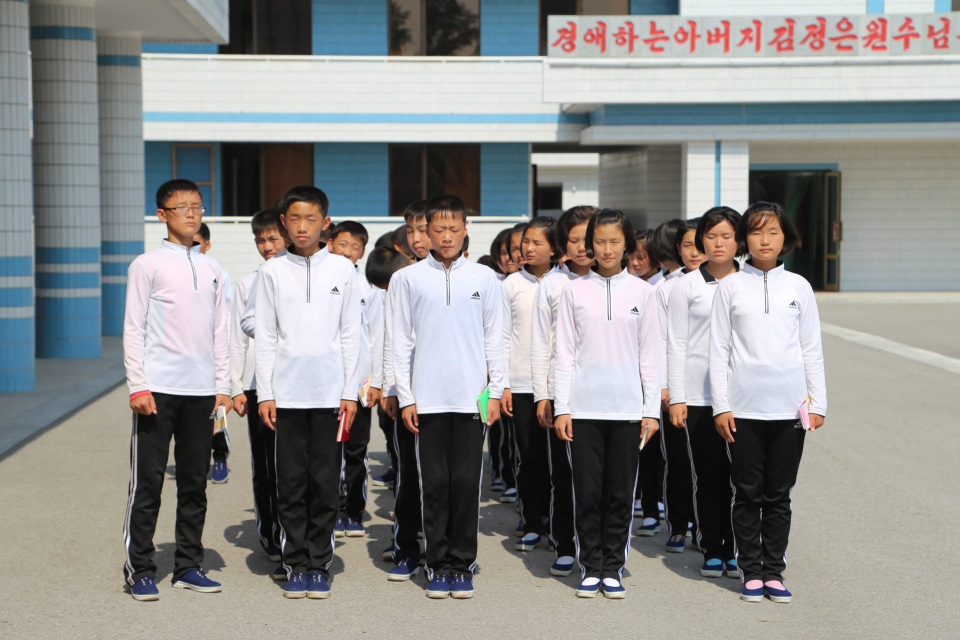Triều Tiên đẹp bình dị qua những góc ảnh hiếm - 24 Học sinh Triều Tiên tập trung trên sân trường để hát ca khúc về nhà lãnh đạo Kim Jong-un. Toàn bộ giày và quần thể thao của các học sinh đều mang thương hiệu Adidas nổi tiếng.