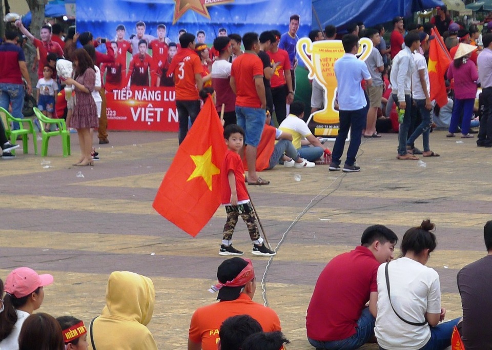 Một nhóc tì... cầm cờ đỏ sao vàng chạy tung tăng trong sân...