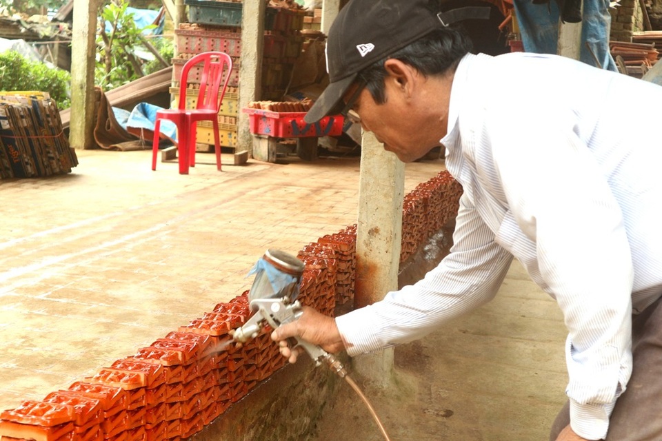 Rộn ràng đúc tượng ông Công, ông Táo ở làng gốm trăm năm tuổi - 9 Lúc trước dùng sơn quét nên rất lâu, sau đó người dân nghĩ ra cách dùng bình phun lên vừa nhanh, màu cũng đẹp hơn
