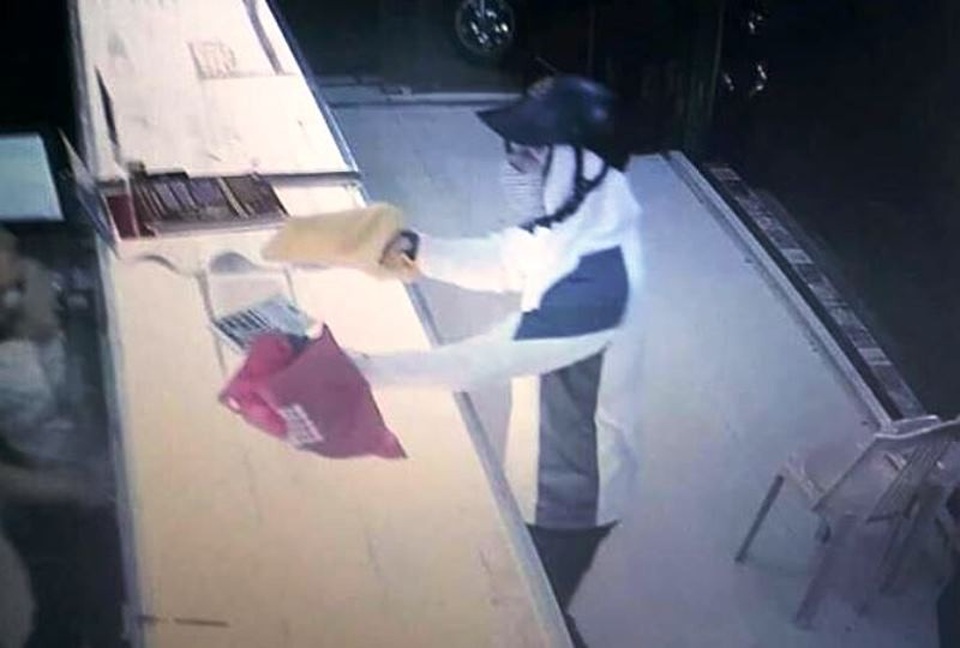 Điều tra, xác minh nghi án nam thanh niên dùng súng cướp tiệm vàng - 1 Đối tượng bịt khẩu trang kín mít, mang mũ bảo hiểm cầm vật giống súng (được che đậy bởi cái khăn mặt màu vàng) (ảnh cắt từ video camera)